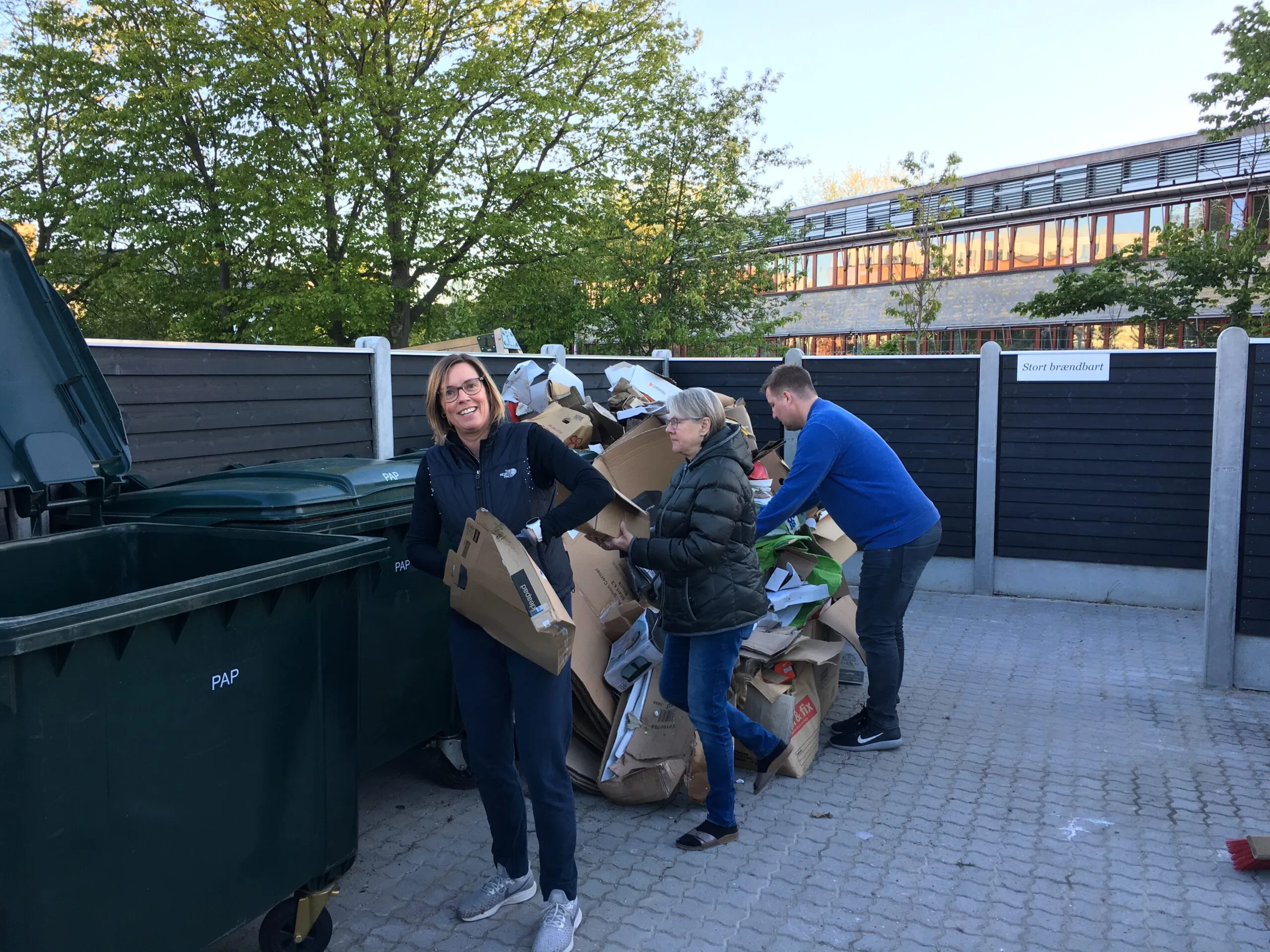 Beboere sorterer pap og papkasser ved foreningens affaldsplads med grønne containere