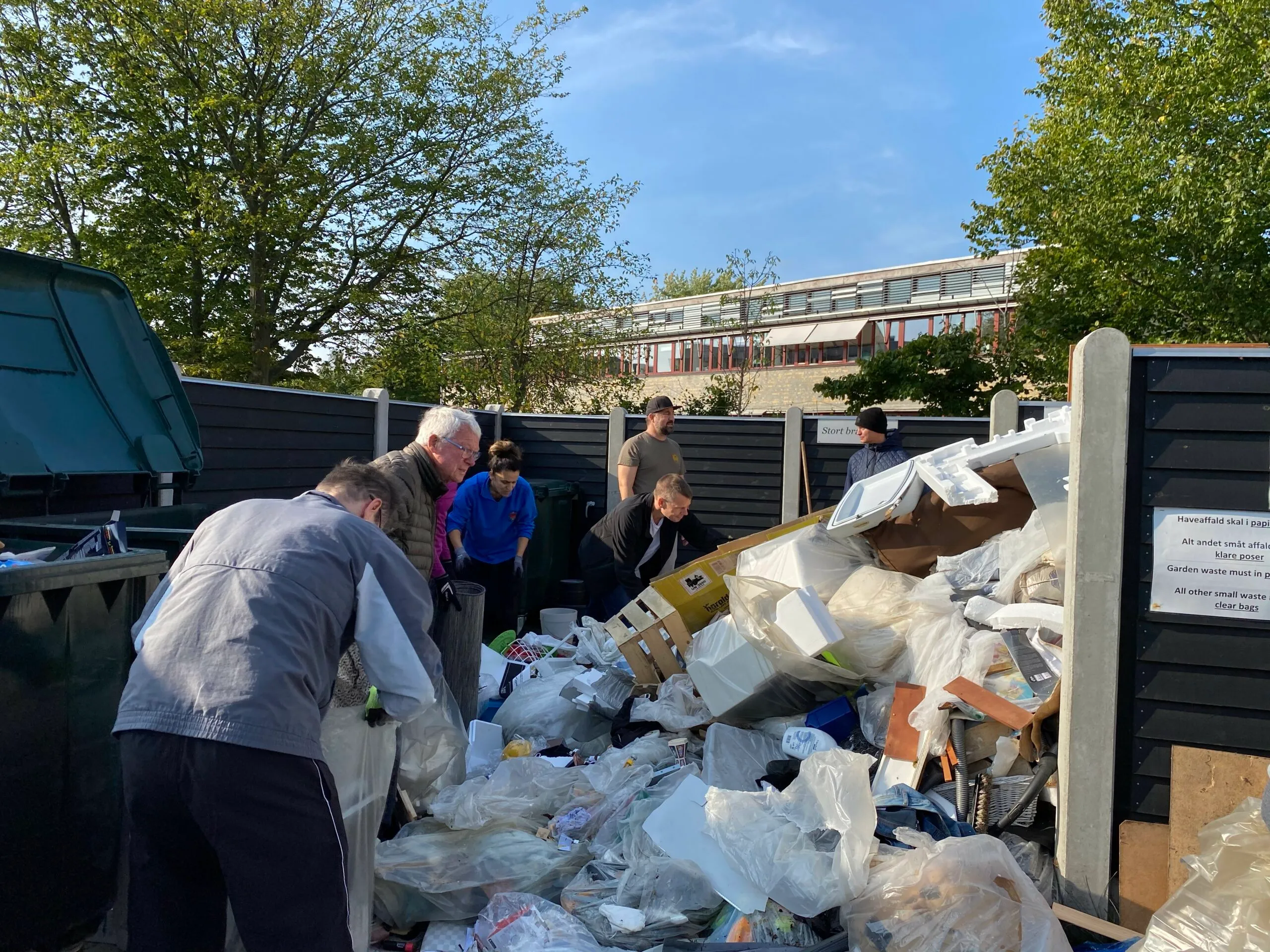 Beboere sorterer storskrald og affald ved foreningens affaldsplads på en solskinsdag
